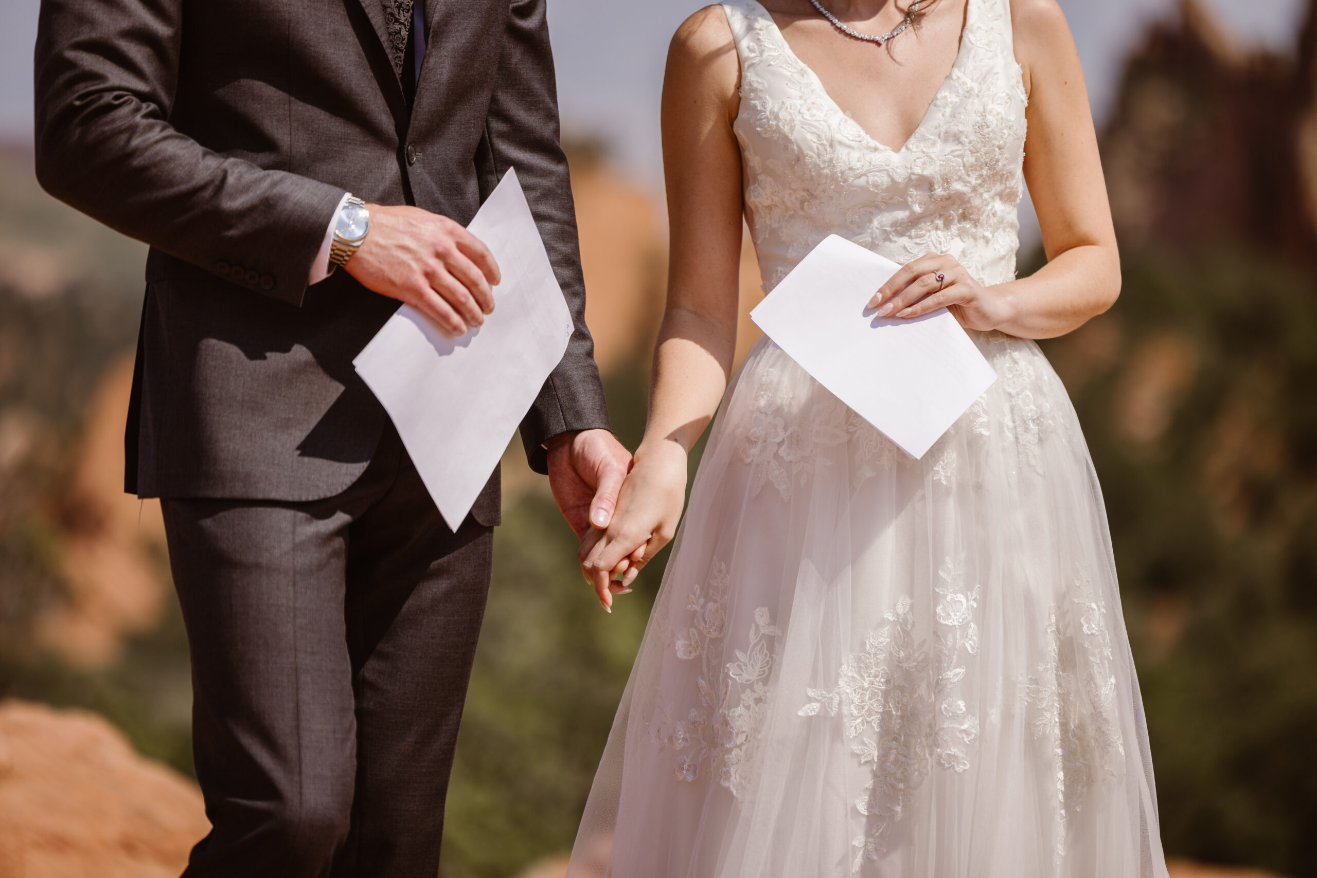 Bride and groom hold hands while reading their vows during an intimate wedding ceremony at Garden of the Gods in Colorado.