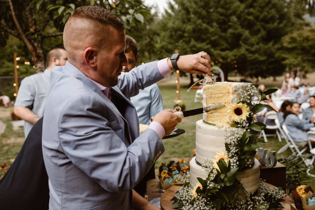 Groomsmen finishing cutting the cake.
