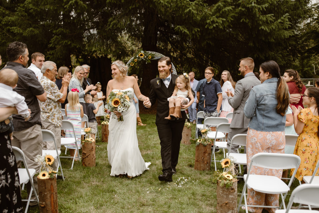 Walking back down the aisle after being married, carrying their daughter