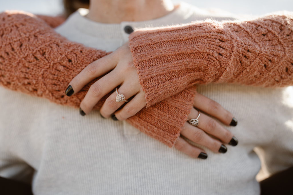 Woman's hands wrapped around her fiancé's neck, showing off her engagement ring