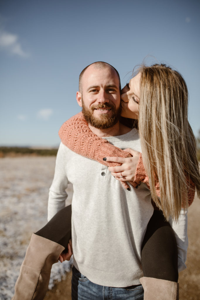 Woman on fiancé's back, woman kissing man's cheek