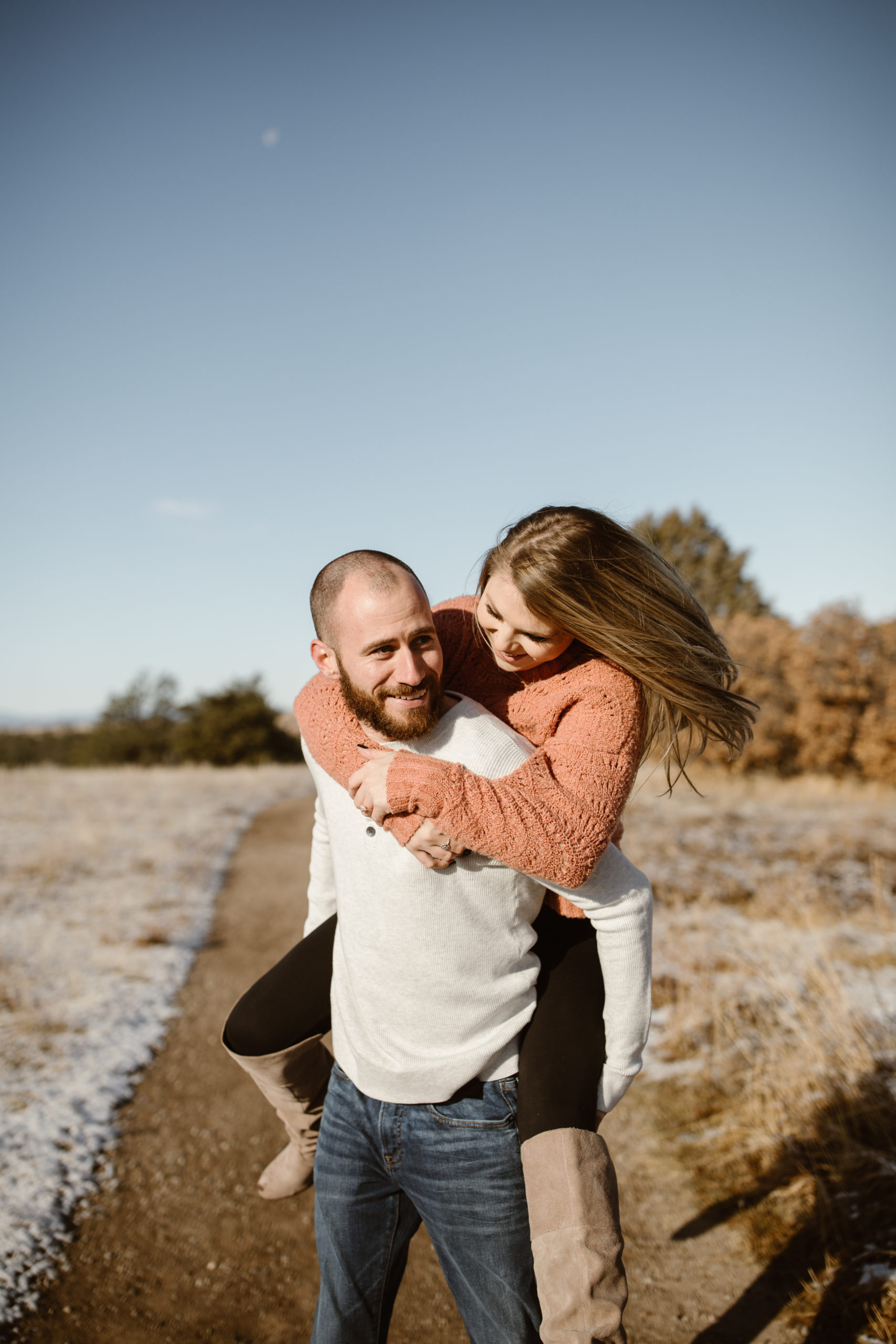 Woman on fiancé's back, both of them smiling