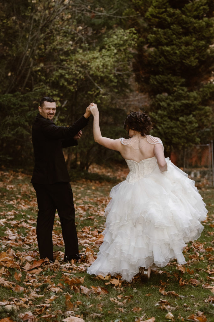 Groom holding bride's hand outside.