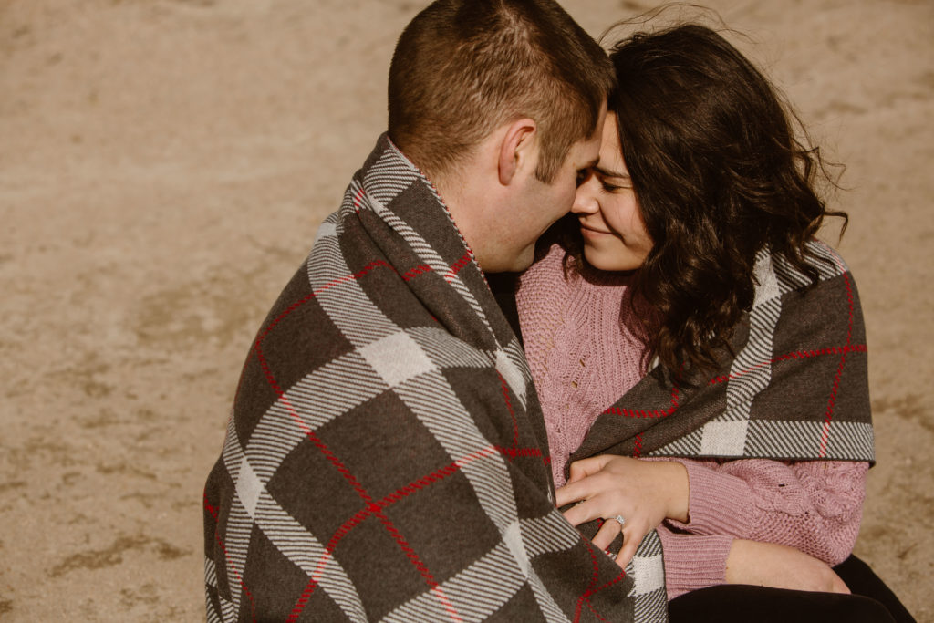 Couple wrapped in a blanket with their foreheads touching