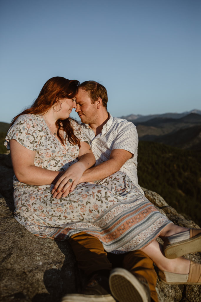 Couple sitting on a rock in the mountains with their foreheads touching