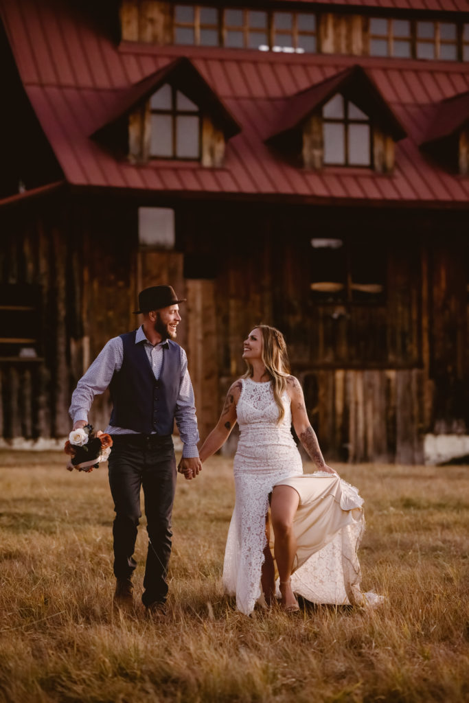 Bride and groom running in a field with a barn behind them