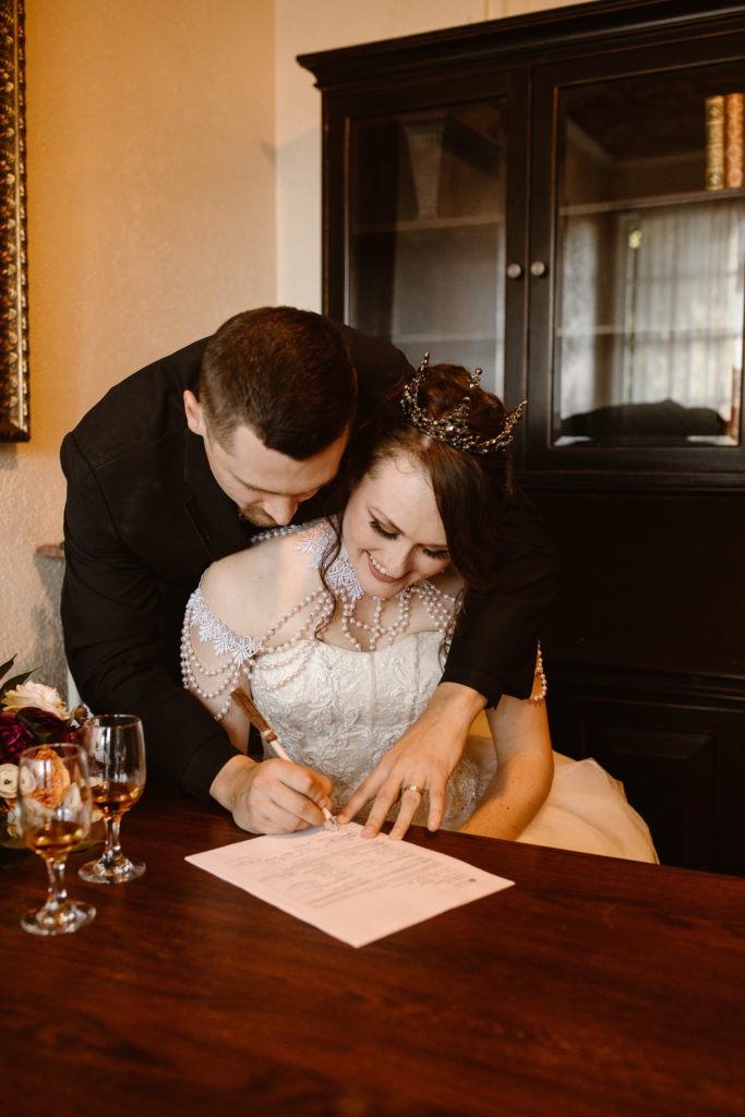 Groom signing marriage certificate with his new wife.
