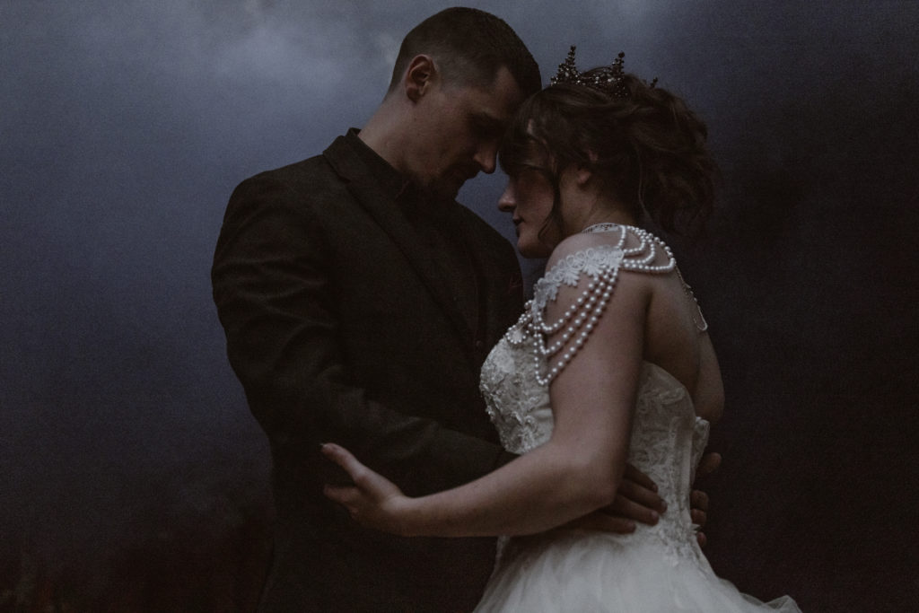 Bride and groom holding hands with colored smoke behind them.