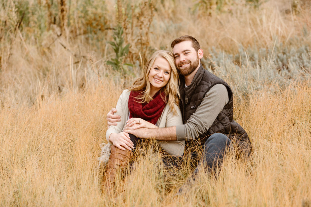 Couple with arms around each other sitting in grass