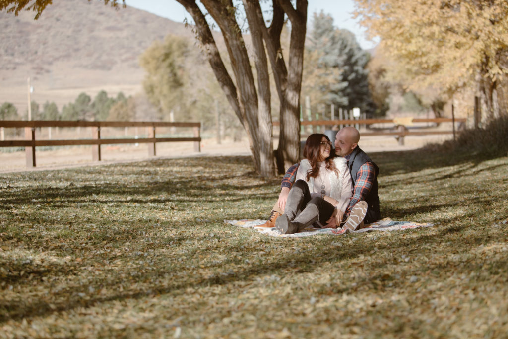 Couple cuddled together on a picnic blanket