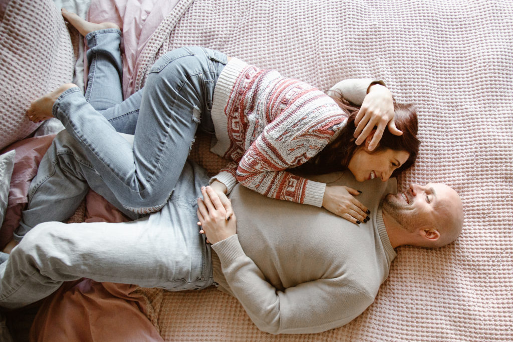 Couple laying on their bed cuddling