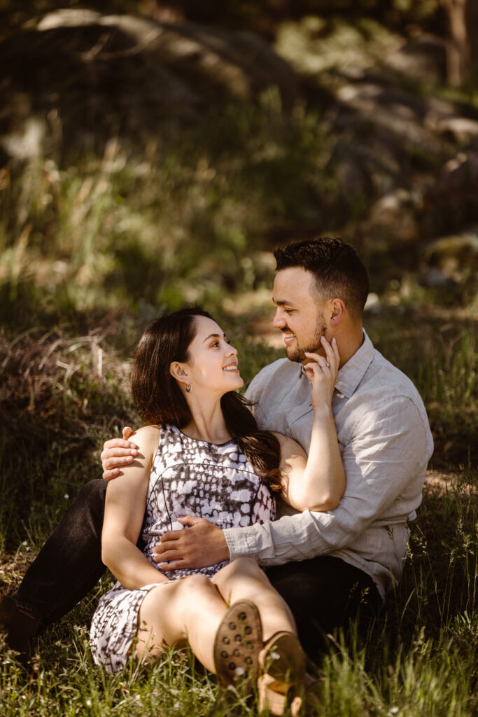 Engaged couple cuddled together in a field