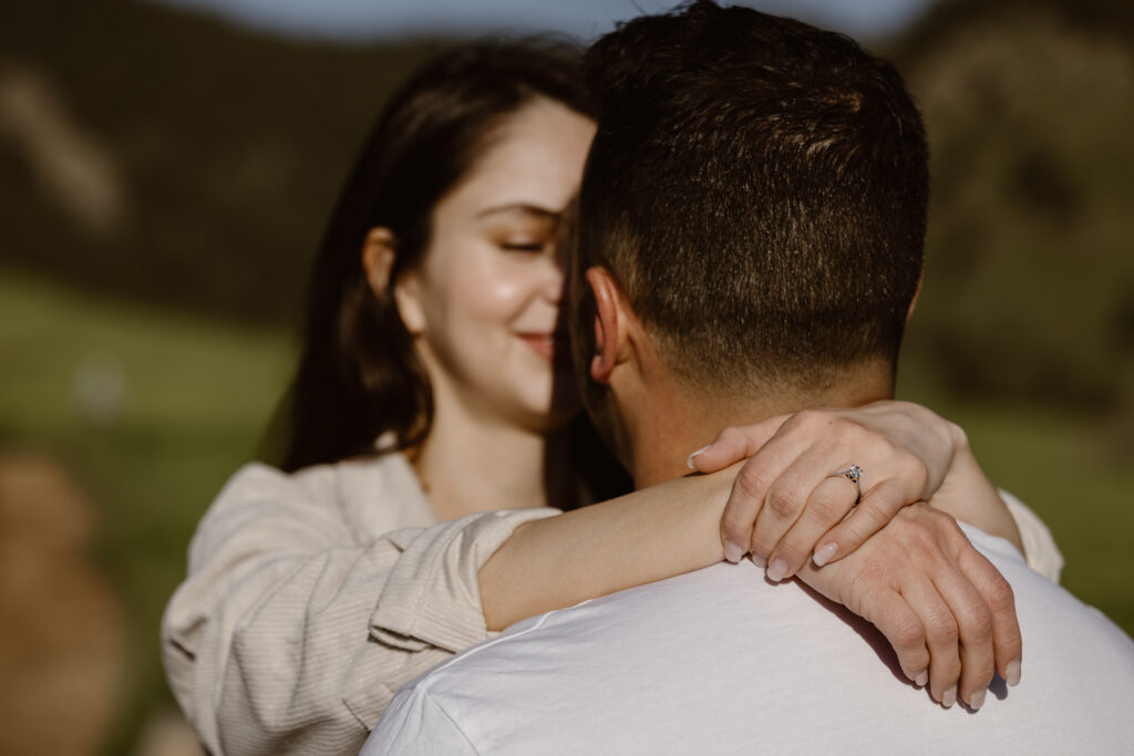 Woman with her arms around her fiancé's neck highlighting her engagement ring