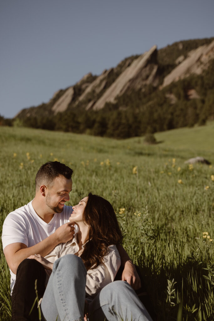 Engaged couple cuddled together in a field