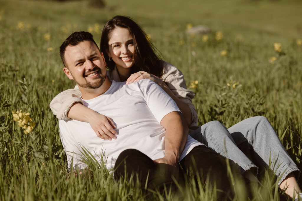 Engaged couple cuddled together in a field