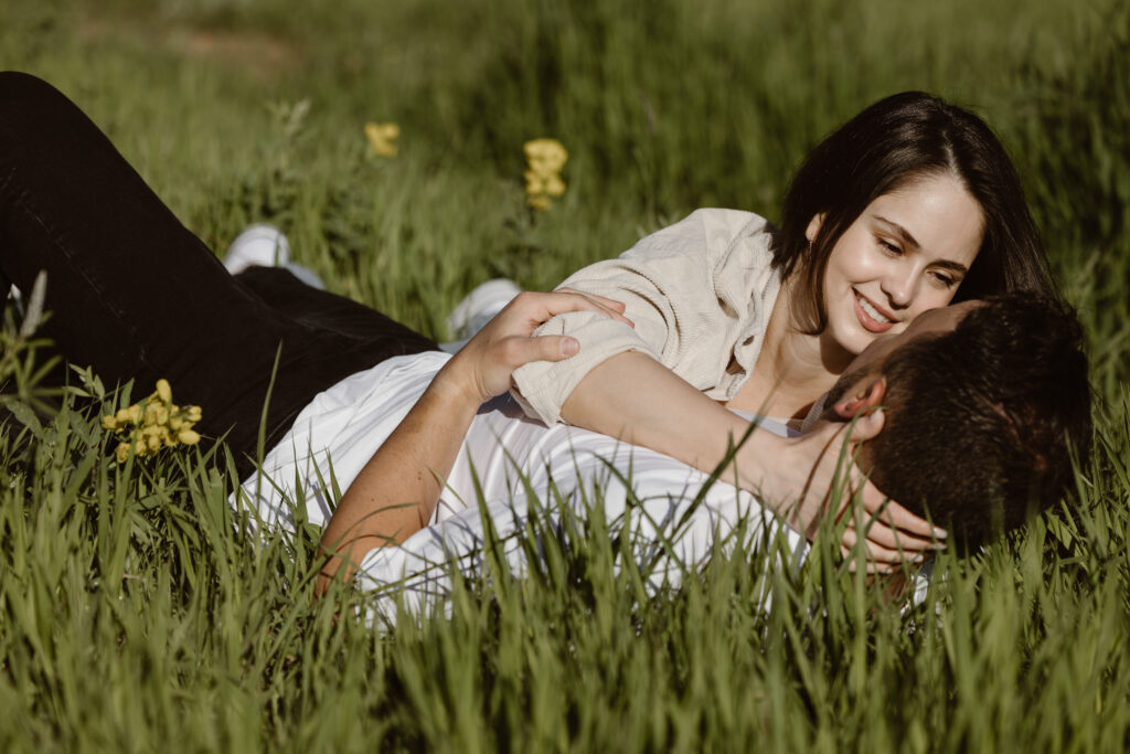 Engaged couple cuddled together in a field