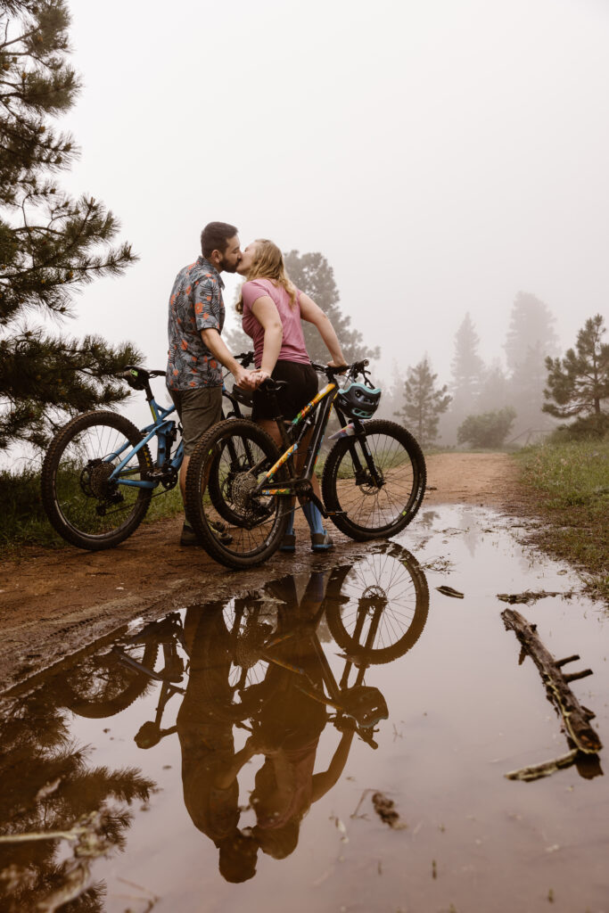 Couple holding their mountain bikes on a dirt path kissing