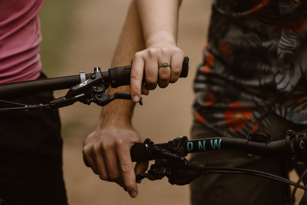 Engaged couple on their bikes standing next to each other. Focused on their hands, highlighting woman's engagement ring