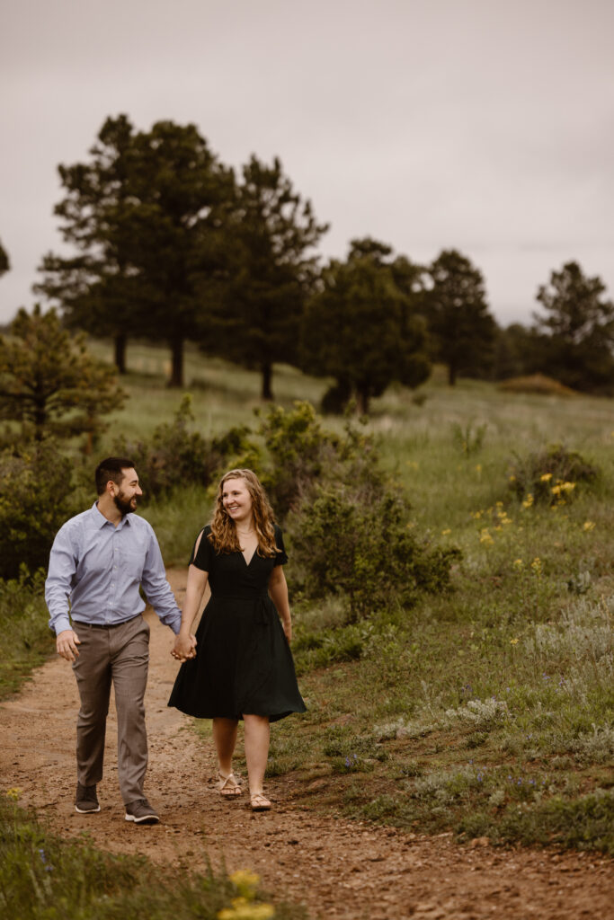Engaged couple walking down a path holding hands