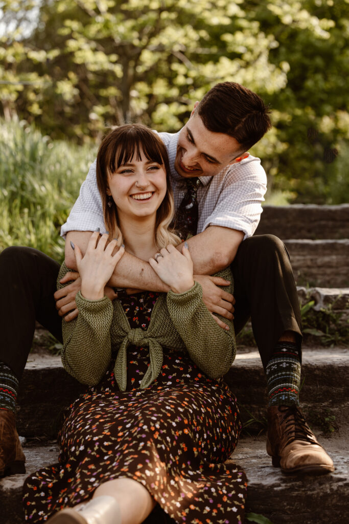 Man behind his fiancé with his arms wrapped around her and they are laughing