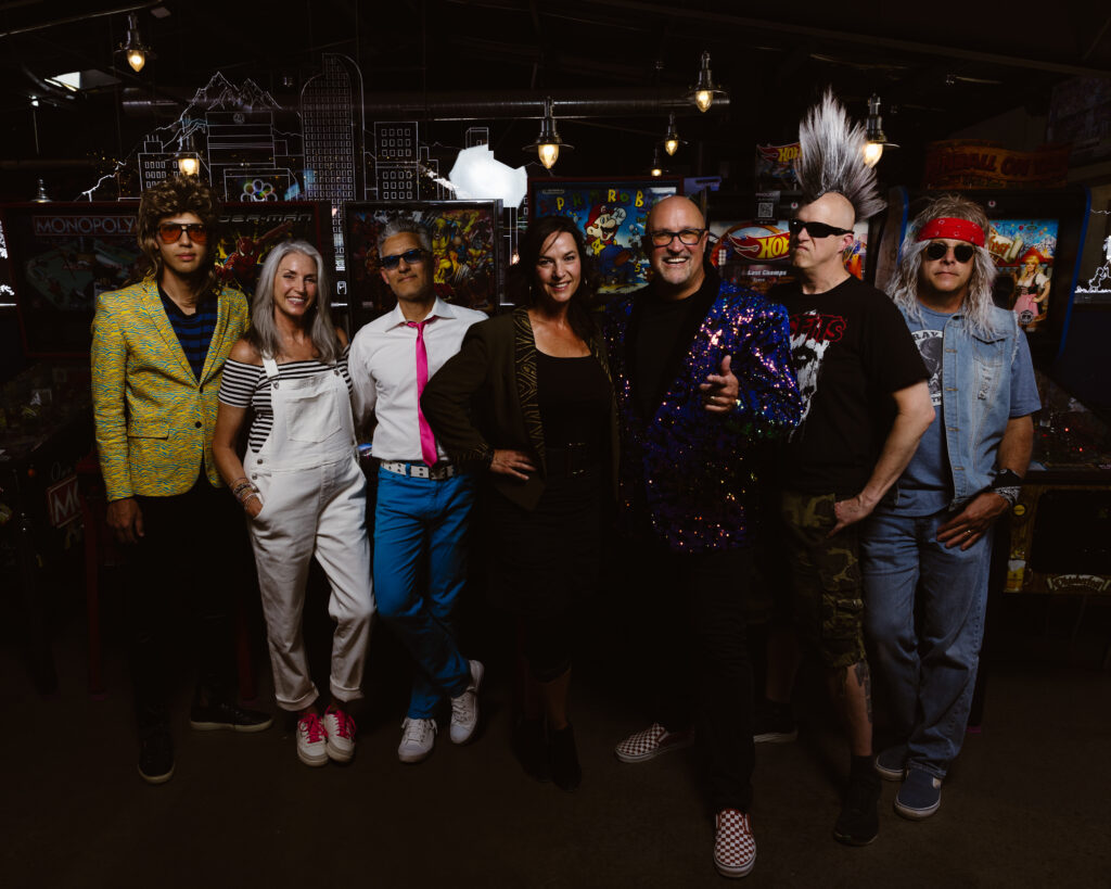 Full band portrait in front of old arcade games
