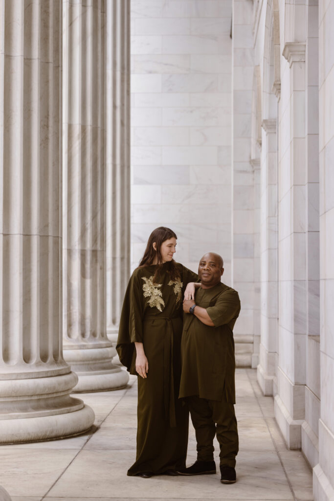Couple in Nigerian outfits smiling woman looking at her fiancé, him looking at the camera