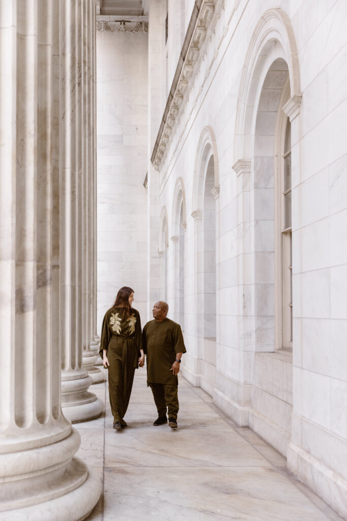 Couple in Nigerian outfits walking in front of a white building with columns