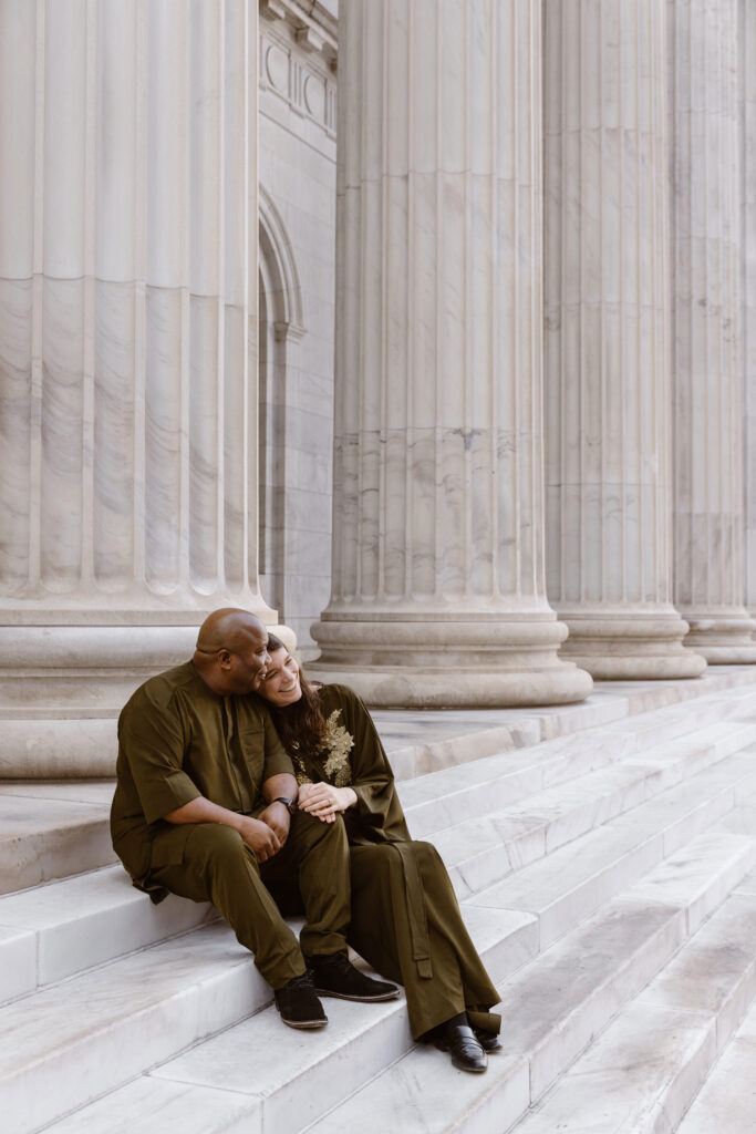 Couple in Nigerian outfits cuddled up on the steps of the Bryan Courthouse