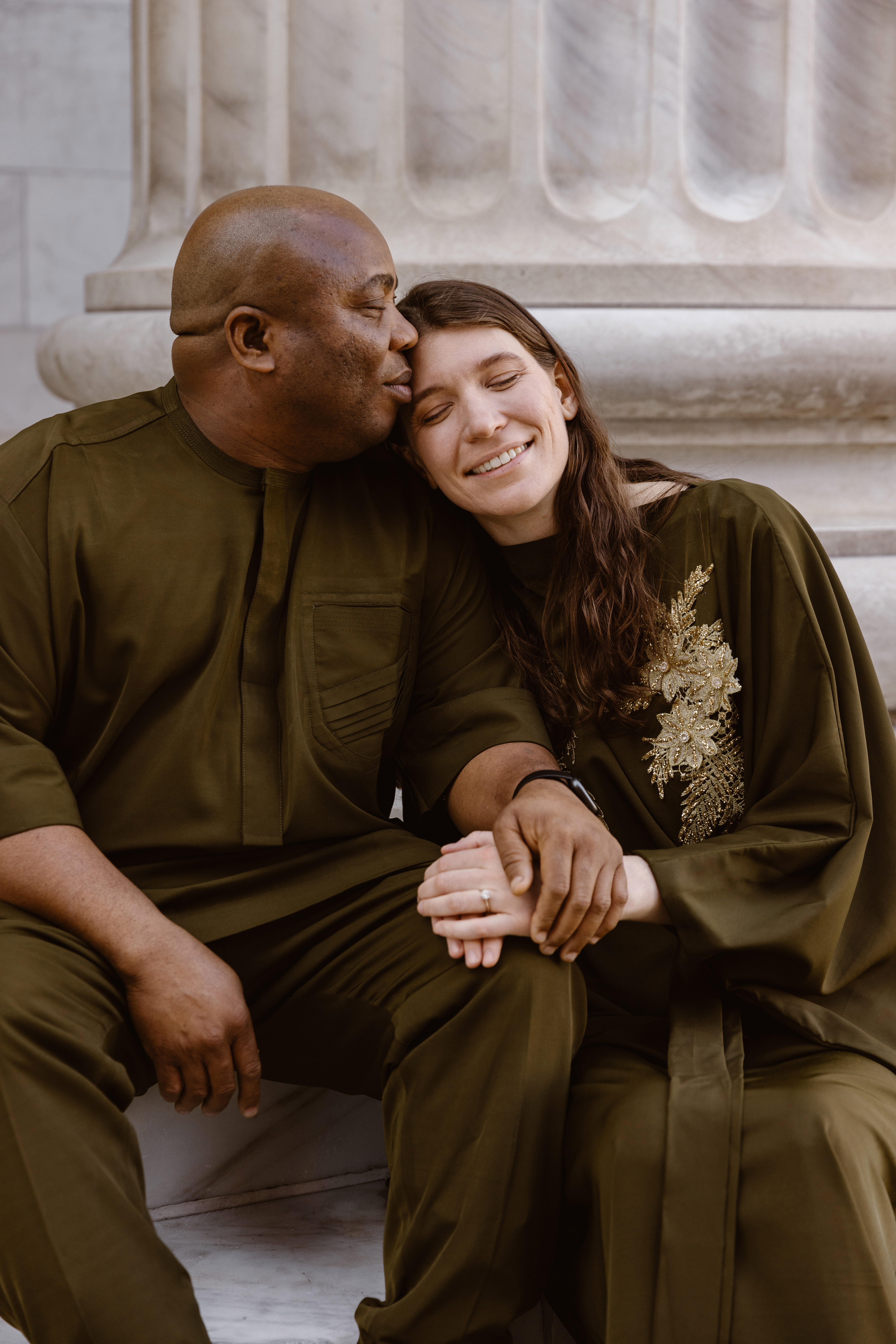 Couple in Nigerian outfits cuddled up on the steps of the Bryan Courthouse