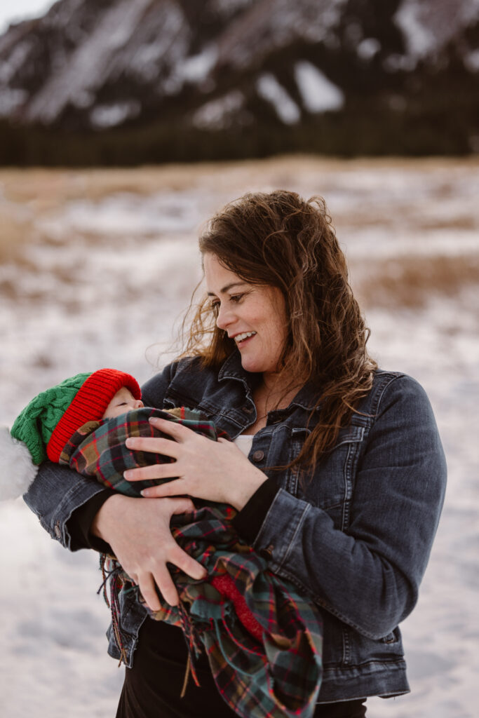 Mother looking at her newborn daughter with snowy Flatirons in the background