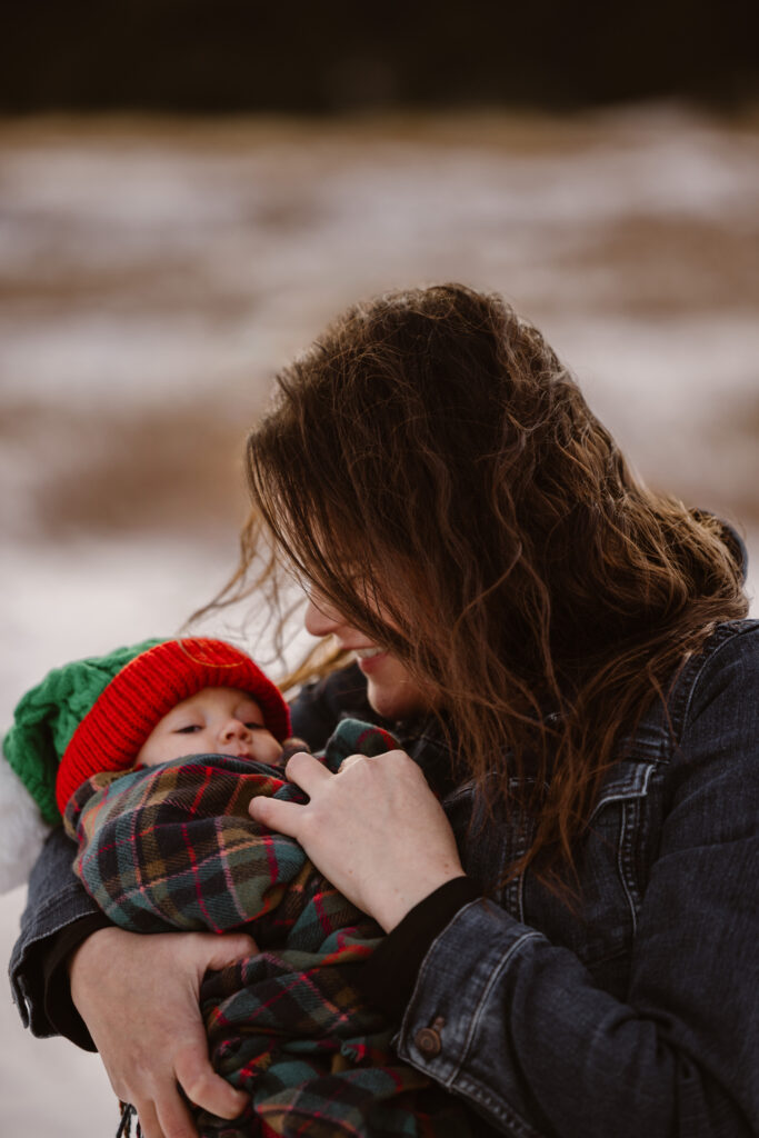 Mother looking at her newborn daughter with snowy Flatirons in the background