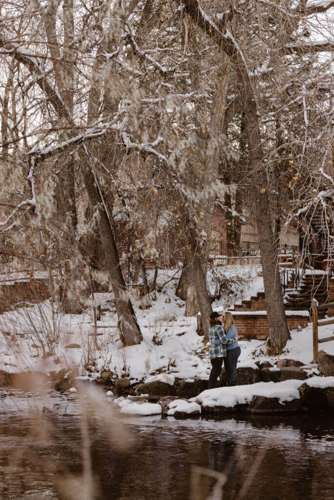 Couple looking at each other together next to a river with snow