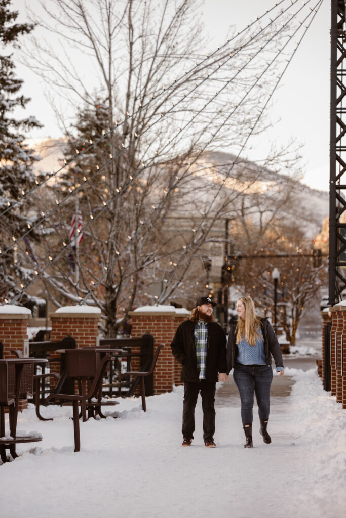 Couple holding hands walking down a snowy sidewalk