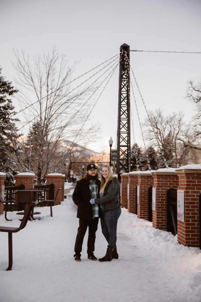Couple cuddled together on a snowy sidewalk