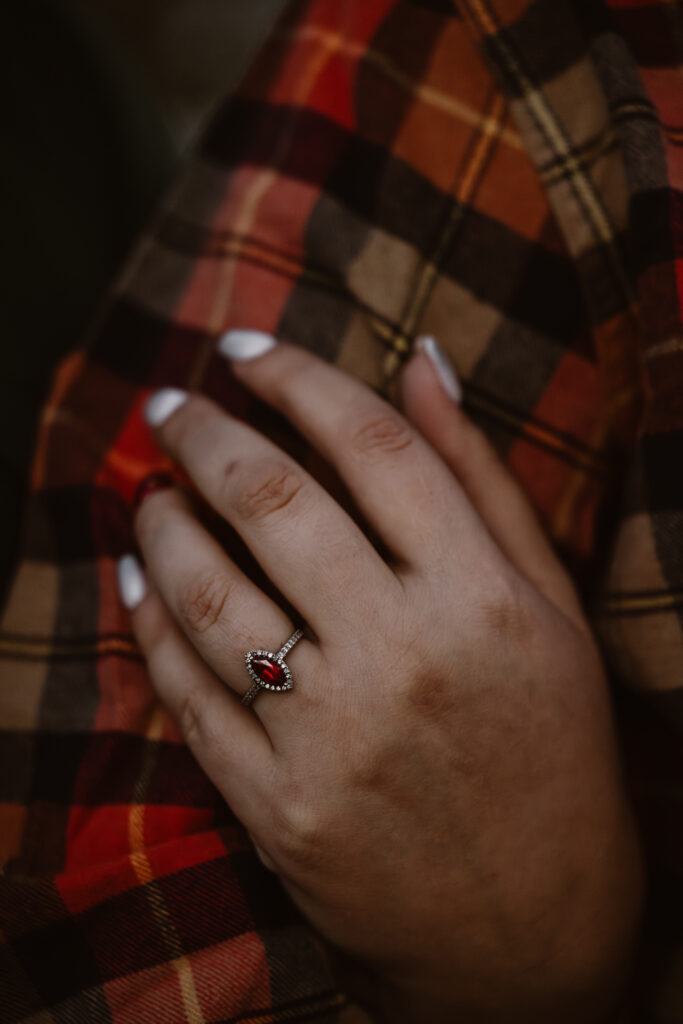 Woman's hand on fiancé's arm highlighting her engagement ring