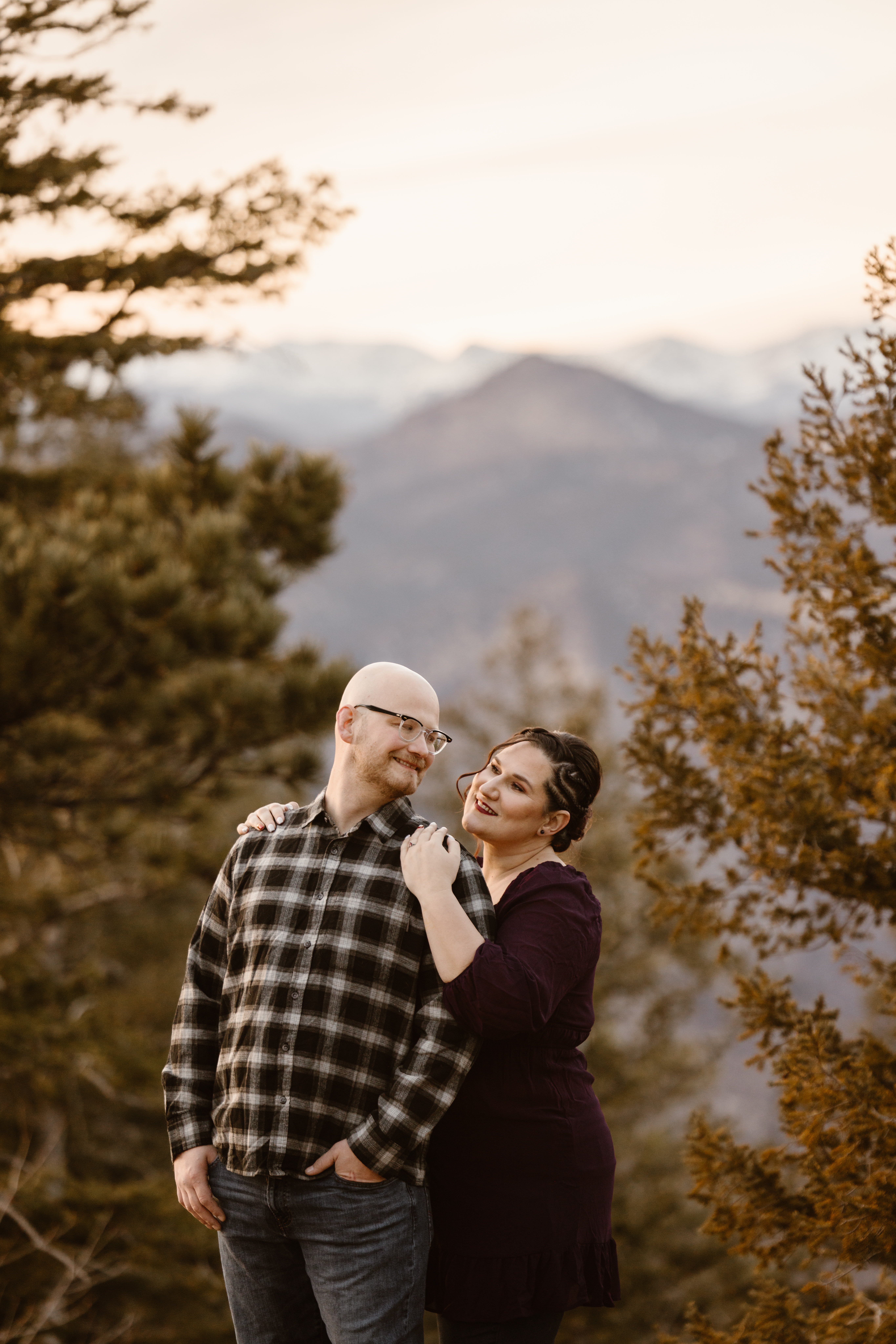 Woman looking at her fiancé with her arms wrapped around him from behind
