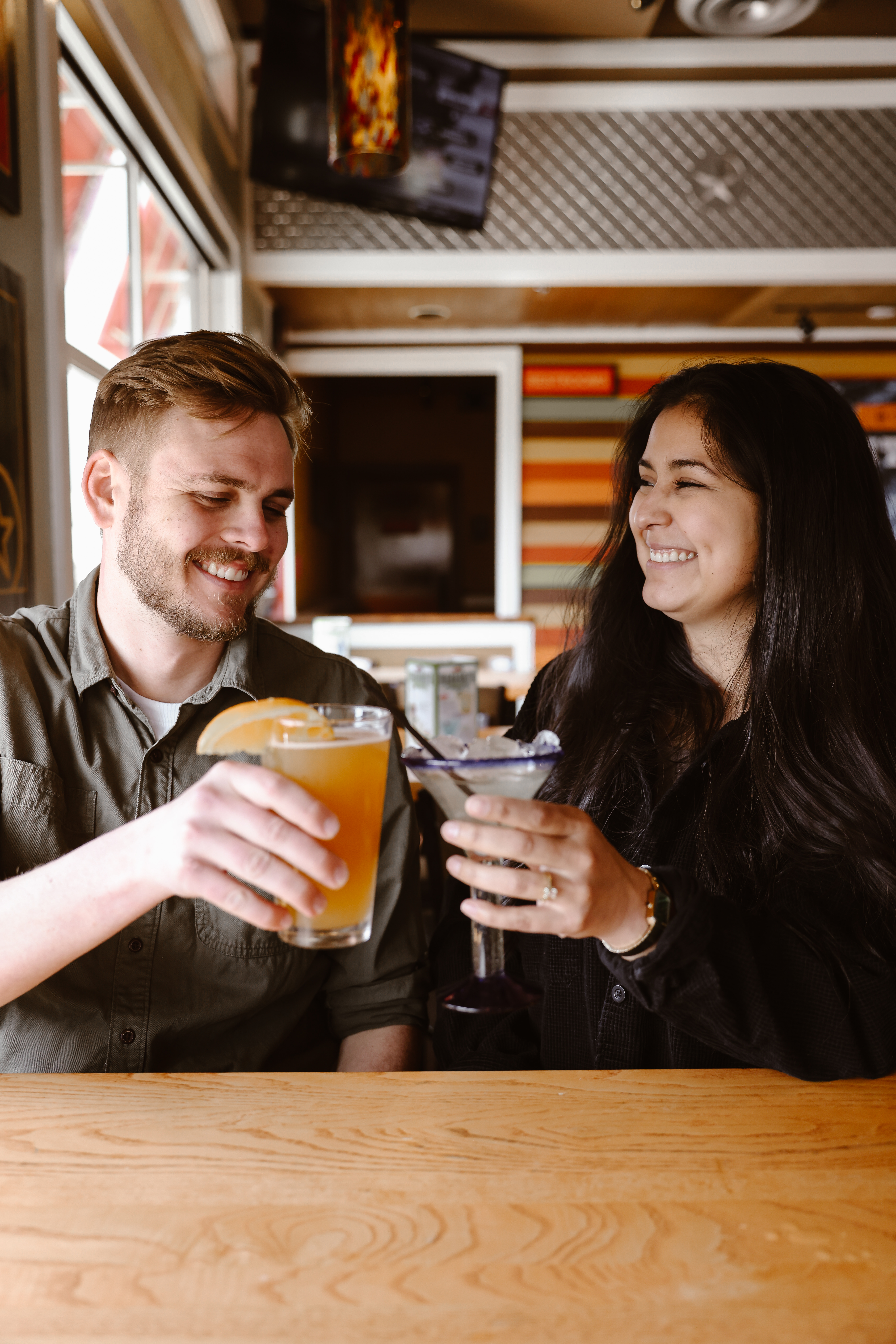 Engaged couple cheersing at a Chili's during a Colorado engagement session in Lafayette, CO photographed by Colorado engagement photographer Simply Cassandra.