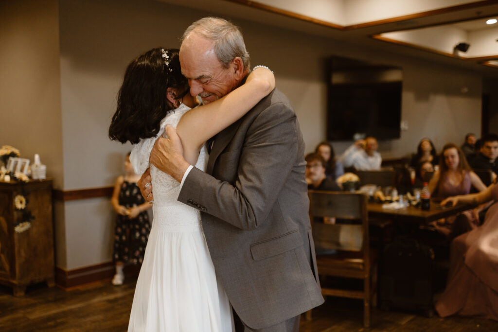 Bride hugging her father during their father-daughter dance at Walnut Creek Golf Preserve wedding reception in Westminster Colorado captured by Colorado wedding photographer.