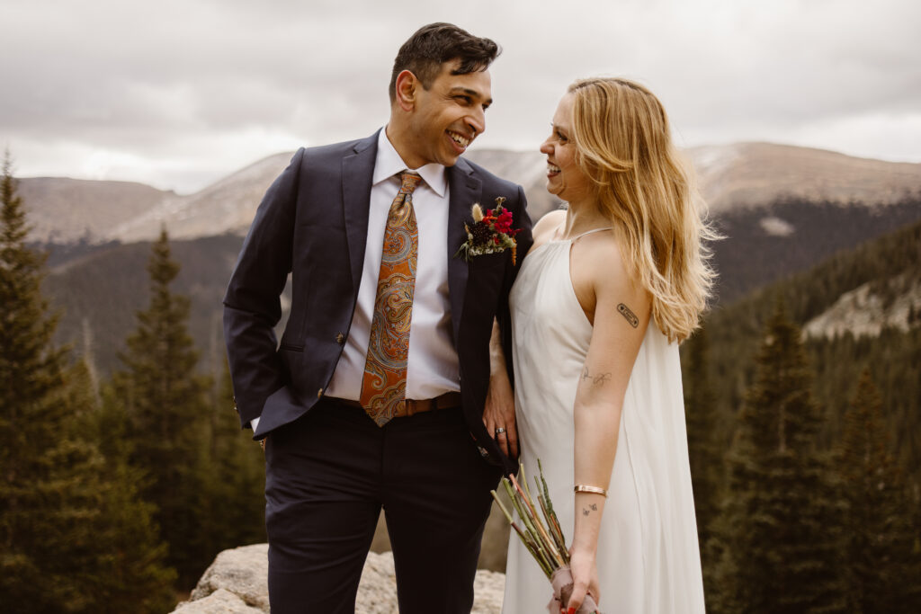 Just-married couple laughing together during an intimate Winter Park, Colorado mountain elopement, surrounded by evergreen trees and alpine views.