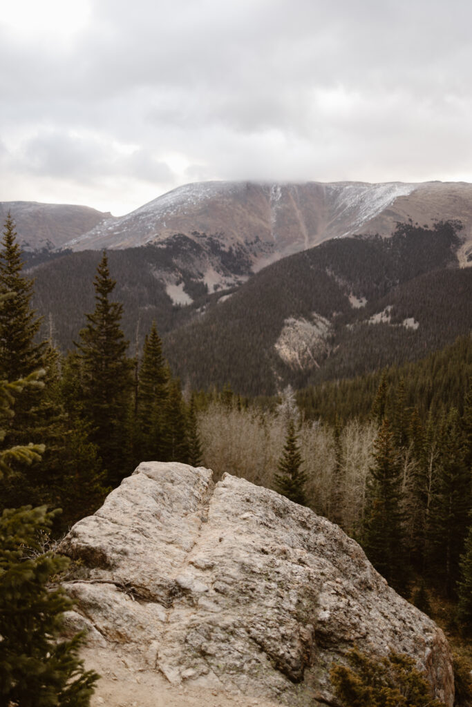 Scenic mountain overlook with evergreen trees and rocky foreground during a Winter Park elopement in Colorado, photographed by Cassie Peterson.