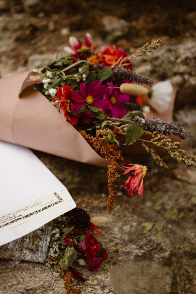 Hand-tied wildflower bouquet resting on a rock during a Winter Park elopement in Colorado, photographed by Cassie Peterson.