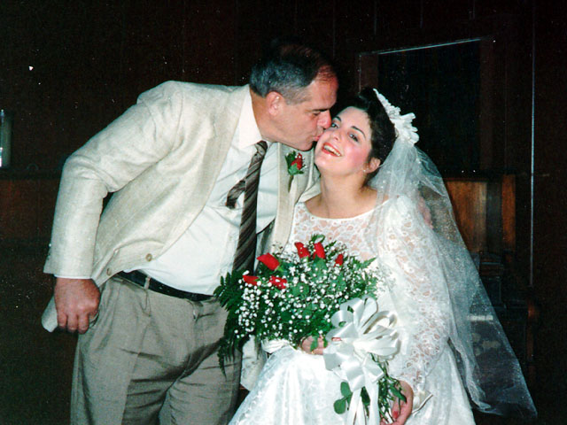Father kissing the bride on the cheek during her vintage Las Vegas elopement ceremony inside a chapel.