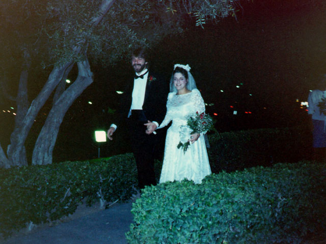 Bride and groom walking hand in hand at night after their vintage Las Vegas elopement ceremony, surrounded by soft outdoor lights.